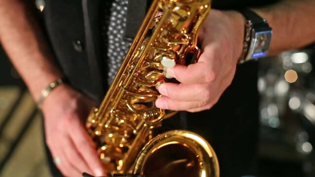 Close up view of saxophonist playing a saxophone in studio.