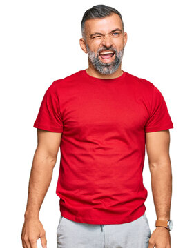 Middle age handsome man wearing casual clothes winking looking at the camera with sexy expression, cheerful and happy face.