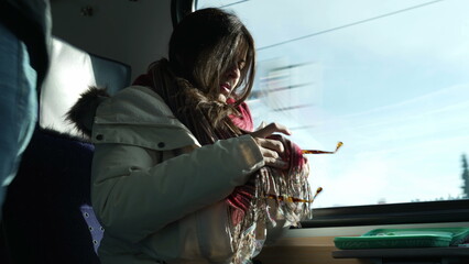 Woman cleaning sunglasses with scarf while traveling by train. Female passenger commuter wiping...