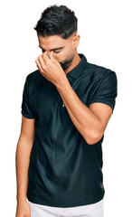 Young man with beard wearing sportswear tired rubbing nose and eyes feeling fatigue and headache. stress and frustration concept.