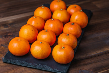clementine mandarin fruit on black stone board.