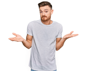 Young redhead man wearing casual grey t shirt clueless and confused expression with arms and hands raised. doubt concept.