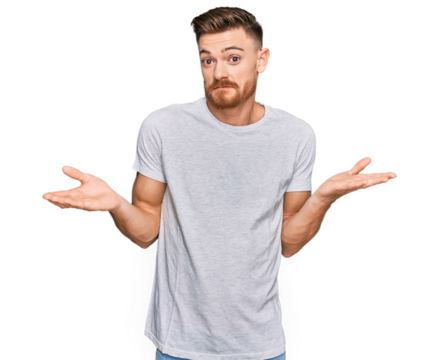 Young redhead man wearing casual grey t shirt clueless and confused expression with arms and hands raised. doubt concept.