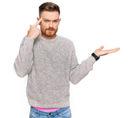Young redhead man wearing casual winter sweater confused and annoyed with open palm showing copy space and pointing finger to forehead. think about it.