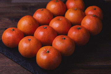 Photo of tangerines lined up in rows on the black stone board.