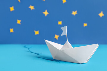 White origami boat with flag and decor on color background