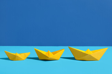Yellow origami boats on color background
