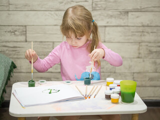 little girl draws with paints.