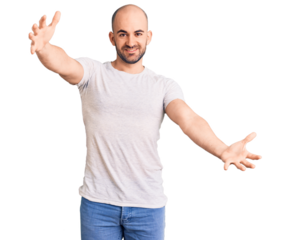 Young handsome man wearing casual t shirt looking at the camera smiling with open arms for hug. cheerful expression embracing happiness.
