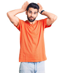 Young handsome man with beard wearing casual t-shirt doing bunny ears gesture with hands palms looking cynical and skeptical. easter rabbit concept.