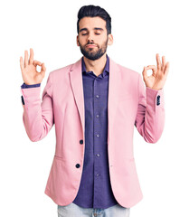 Young handsome man with beard wearing elegant jacket relax and smiling with eyes closed doing meditation gesture with fingers. yoga concept.