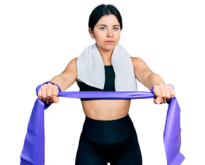 Young brunette woman with blue eyes training arm resistance with elastic arm bands relaxed with serious expression on face. simple and natural looking at the camera.