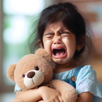 Menina chorando segurando ursinho fofinho de pel&uacute;cia