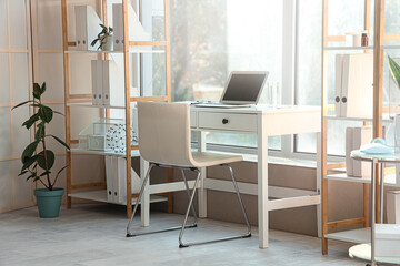 Doctor's workplace with laptop and shelf units in medical office