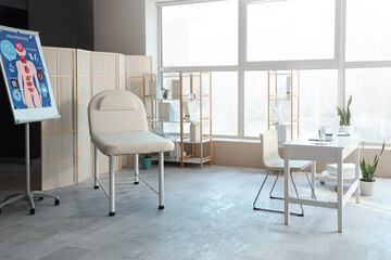 Interior of medical office with workplace, couch and folding screen