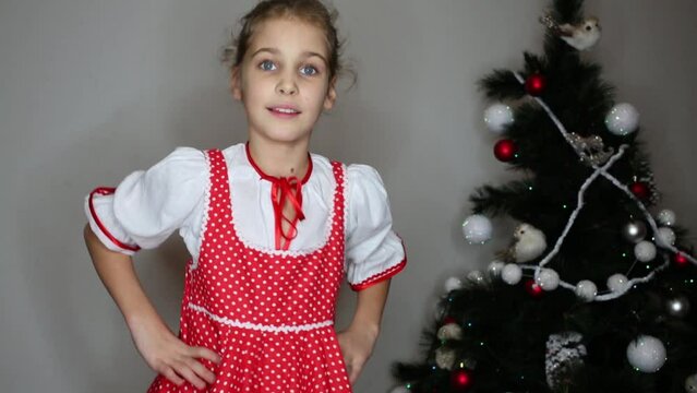 Smiling girl dressed in white blouse and red pinafore dress dances