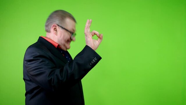 Positive senior man in black suit nods his head and shows ok gesture.