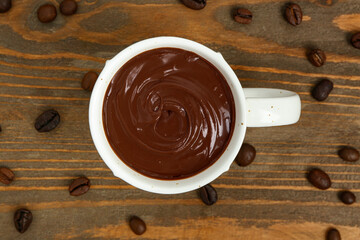 Composition with cup of tasty melted chocolate and coffee beans on white background, closeup
