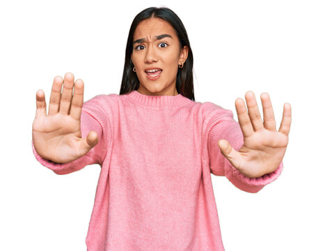 Young asian woman wearing casual winter sweater doing stop gesture with hands palms, angry and frustration expression