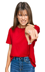 Teenager caucasian girl wearing casual red t shirt pointing displeased and frustrated to the...