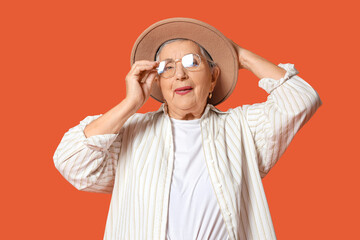 Senior woman in hat on orange background