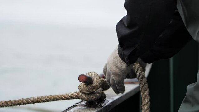Close-up of hands tying boat with rope Boat secured by rope safety in water travel. Boat and rope essentials in sea journeys Quintessential scene of maritime life duo for safe sea travels.