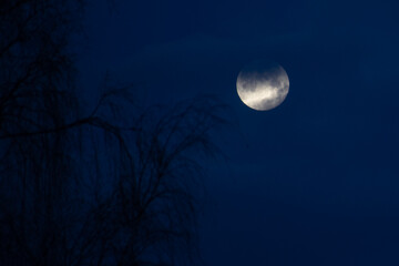 The moon in the evening sky in a dark sky. Soft selective focus. Artificially created grain for the...