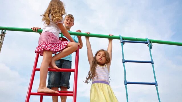 Three cheerful children at the top of playground equipment.