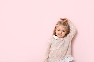 Cute little girl measuring height on pink background