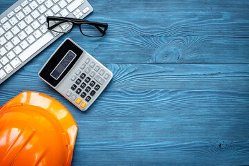 Construction helmet with calculator on builders or designers desk. Architectural project concept