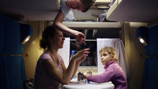 Mother and son look photos on touch phone in speeding train