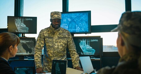 African American naval general coming in office for conference and talking to Caucasian women about marine dislocation. Planning of militarian operation at army staff meeting.