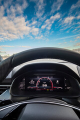 Digital rpm screen dashboard infotainment on a sports car on a blue landscape sky 