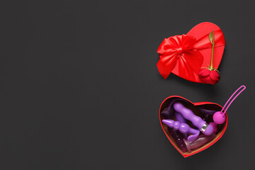 Gift box with beautiful rose flower and different anal plugs from sex shop on black background