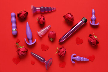 Composition with beautiful rose flowers and different sex toys on red background