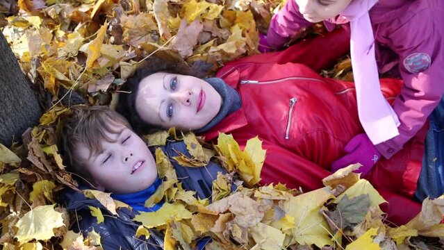 Mother and her son lie on leaves and daughter lies on mother