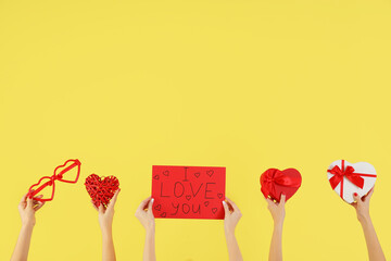 Female hands holding sign with text I LOVE YOU, heart-shaped gift boxes and novelty glasses on...