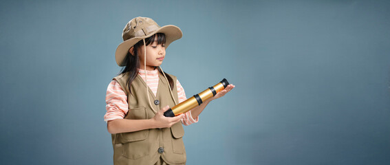 Little girl wearing camping clothes, holding binoculars for studying.