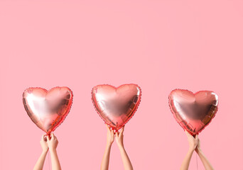 Female hands holding heart-shaped balloons on pink background. Valentine's Day celebration