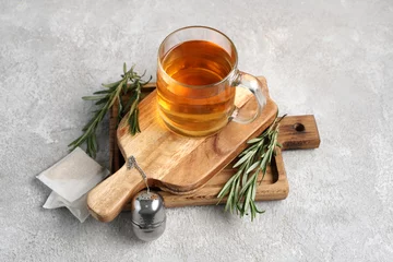 Foto op Plexiglas Wooden board with glass cup of hot rosemary tea on grey background © Pixel-Shot