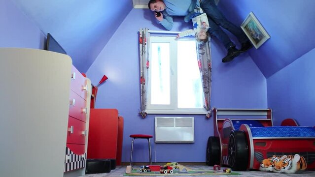 Father and daughter talk phones on ceiling at inverted house