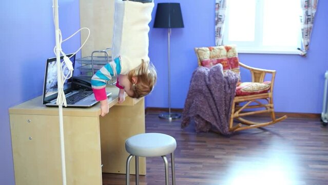 Little girl in jeans gets under table in inverted house
