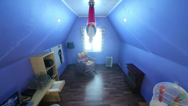 Little girl stands on ceiling upside down at inverted house