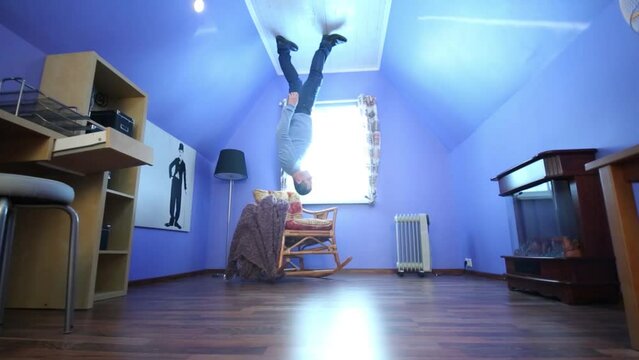 Man on ceiling upside down in blue room in inverted house