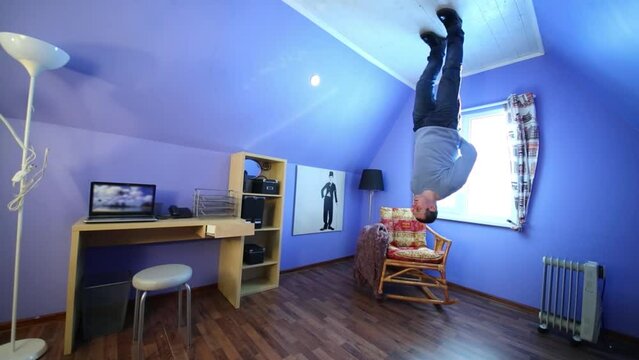 man in jeans stands upside down in inverted house at sunny day
