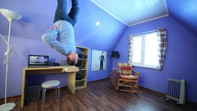 man in jeans goes upside down in inverted house at sunny day