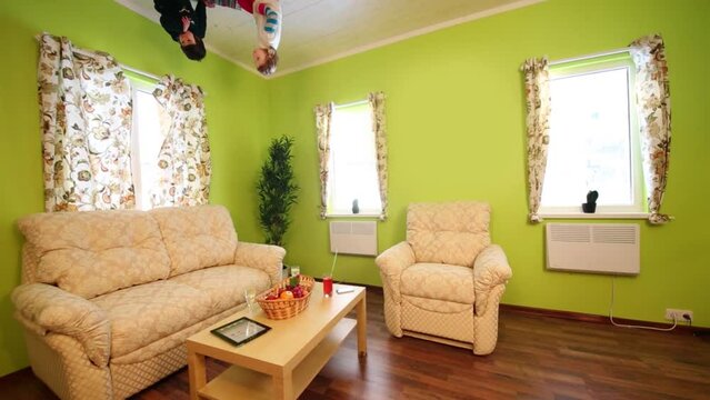 boy and girl upside down sit on ceiling and eat in inverted house