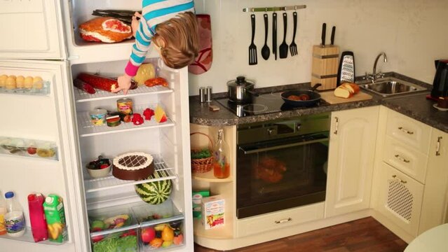 Little girl upside down stands near fridge in inverted house