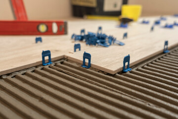 Repair and construction. Laying ceramic tiles using cement on the floor close-up. A man lays slabs on the floor and walls.