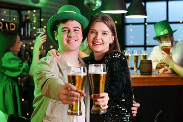 Young couple with beer celebrating St. Patrick's Day in pub